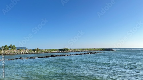 Canvastavla A breathtaking coastal scene featuring crystal-clear blue water, a rocky breakwa