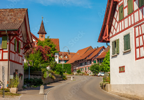 Tableau sur toile Picturesque winding street in a traditional Swiss village lined with beautiful h