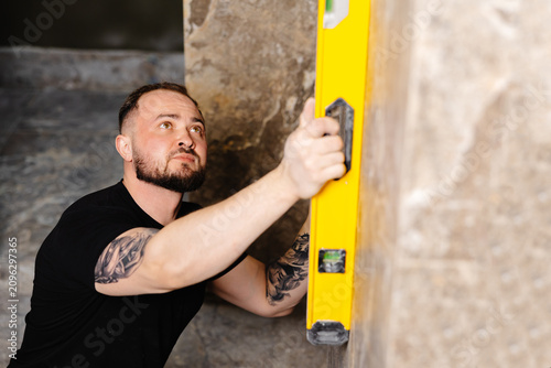 Canvastavla Construction worker using spirit level installing marble tile on wall