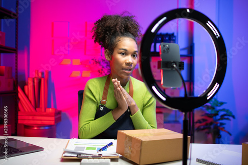 Small online sellers are live-streaming their sales.Young woman confidently films an online product review in studio. Perfect for influencer marketing and digital content creation.