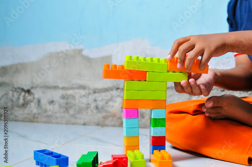 Close up view of a kid playing and stacking colorful plastic toy building blocks on the floor, focusing on fine motor skills development and screen-free creative activity.