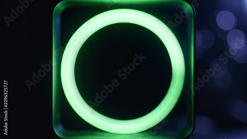 Glowing green neon circle ring light on dark background with bokeh effect