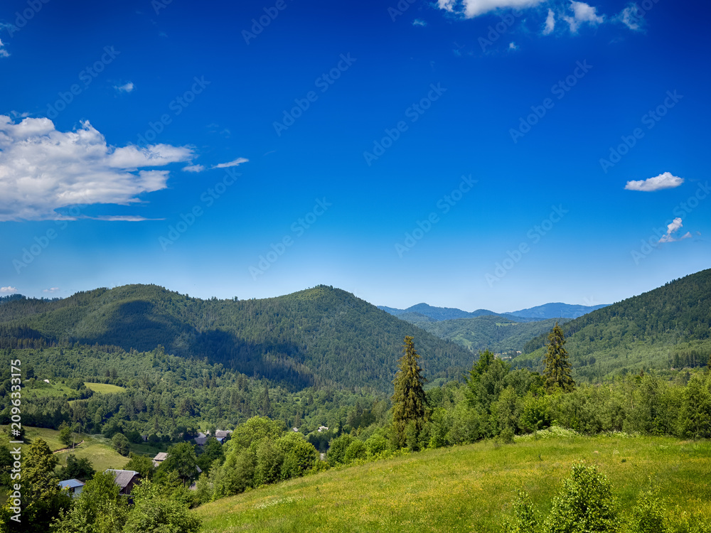 Fototapeta premium Sunny Carpathian peaks: green valleys and cloudy white skies.