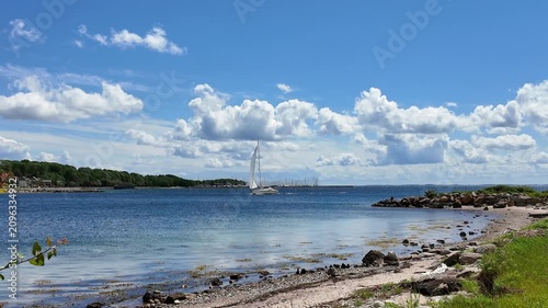 Sailing yacht on Flensburg Fjord near Sonderborg beneath dramatic clouds with calm Baltic Sea water and a peaceful summer atmosphere.