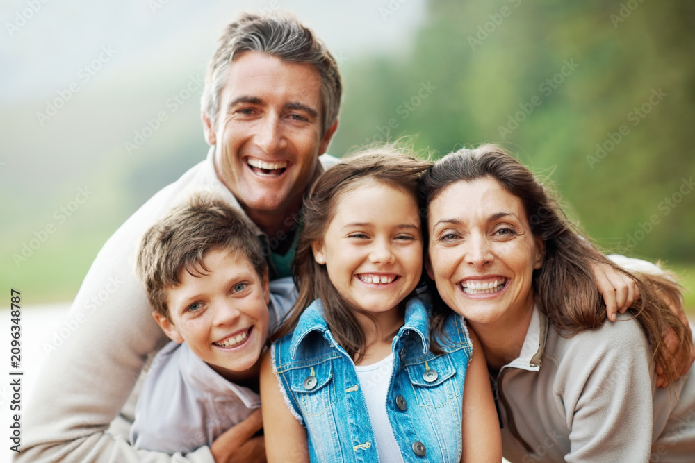 Obraz premium Portrait, nature and happy family with hug for outdoor bonding, holiday or adventure together. Dad, mom and children with smile or embrace in wilderness for travel, weekend trip or vacation in forest