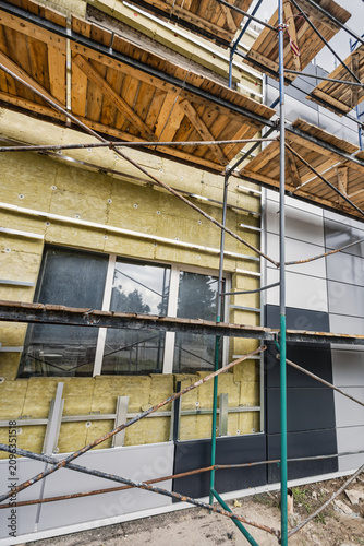 Fotografie Workers install mineral wool insulation on the building's facade
