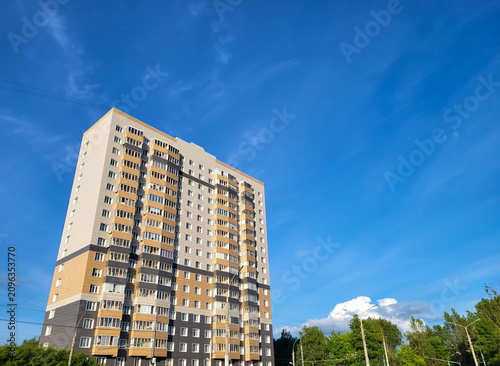 On a clear sunny day, the sky above a high-rise building is blue with a white cloudy haze