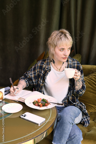 Unique moments of a non binary soul in a cozy cafe enjoying meals and creativity.