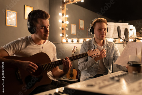 Male musicians reading song lyrics. Men in recording studio