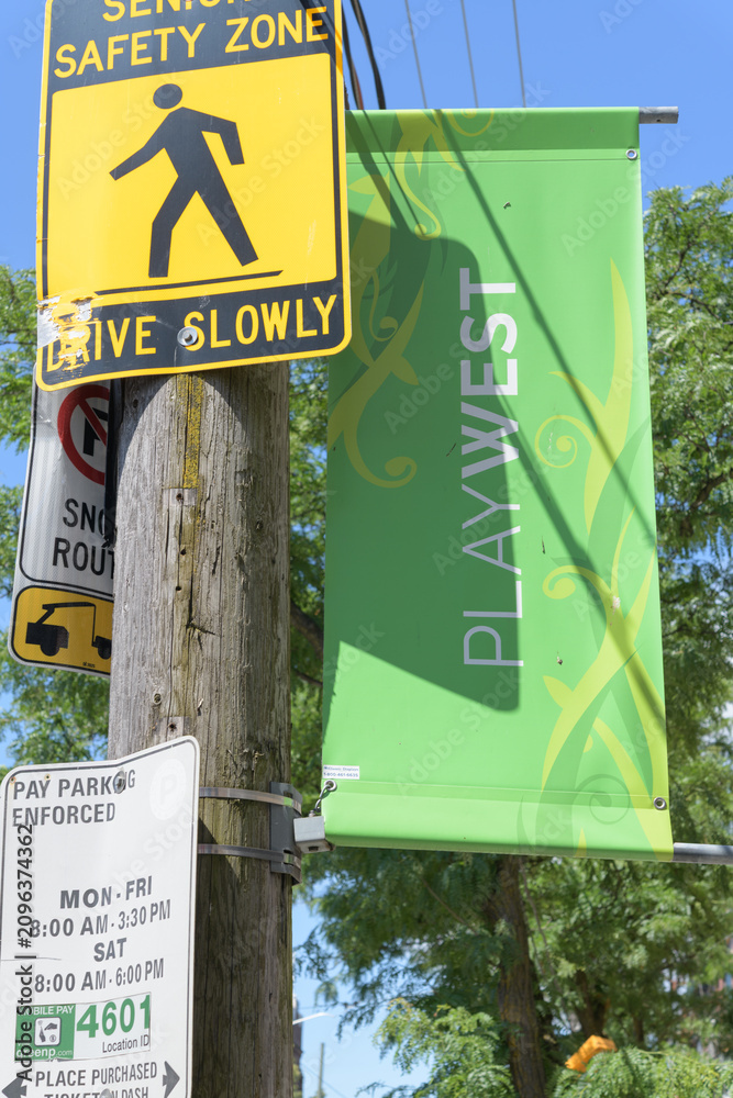 Obraz premium pole-mounted, projecting Play West banner on College St, Toronto (with traffic signs)