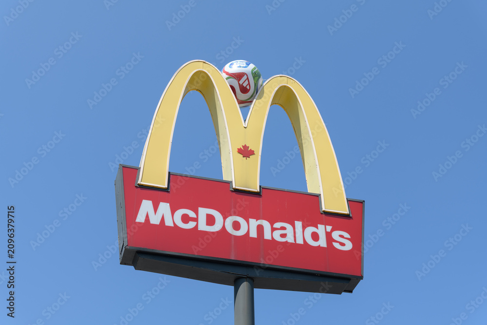 Fototapeta premium iconic Golden Arches and sign of McDonald's Canada fast food restaurant located at 710 St Clair Av W, Toronto - with Trionda soccer ball by Adidas cf FIFA World Cup 2026 