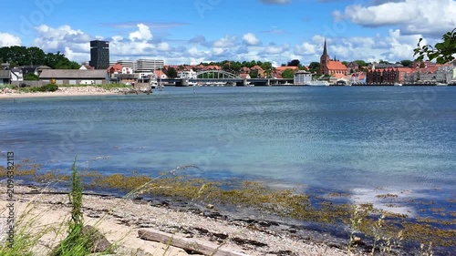 View of Flensburg Fjord near Sonderborg featuring a sandy beach, historic city, calm water along the Baltic coast.