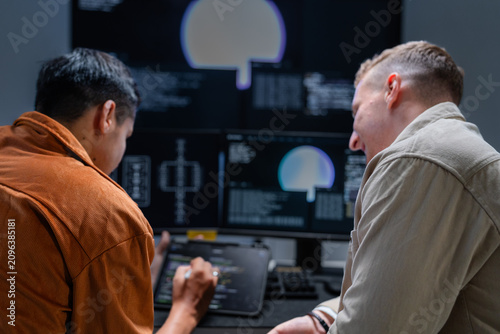 Fotografija A network security analyst directs attention to code on the shared display in a high-tech cyber defence war room, analysing security alerts and defending critical infrastructure