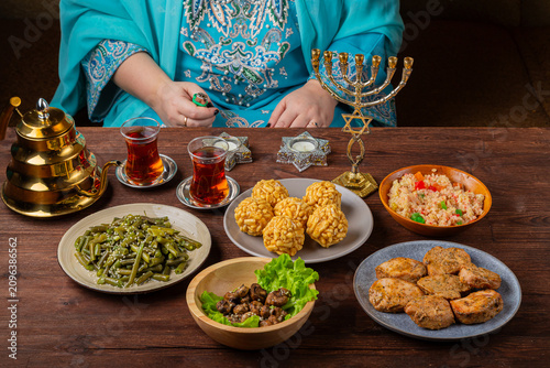 Foto A Jewish woman's hands light Shabbat candles at a set table.