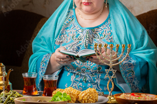 Cuadro en lienzo A Jewish woman prays from the siddur at a table with lit Shabbat candles