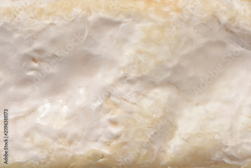 A macro close up of the thick white mold rind on the side of a brie cheese wedge