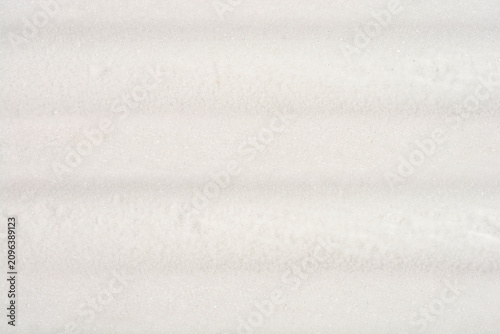 Foto A detailed full frame close up captures the crystalline texture and subtle horizontal lines of ice and white frost buildup on a freezer surface