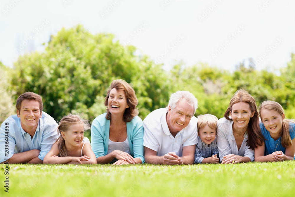 Obraz premium Portrait, family and parents in park with children, relax together and generations bonding on weekend. Happy, mature people and grandma outdoor on grass with grandfather, kids and rest for wellness.