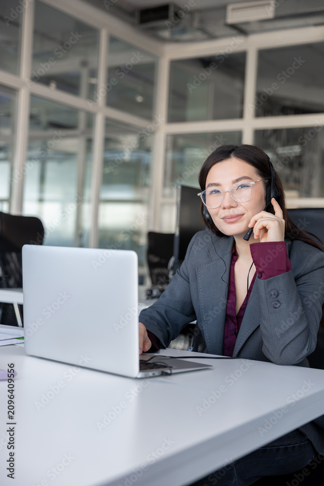 Fototapeta premium Busy woman sitting in the office and having a phone call