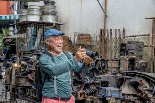 Fotografía Senior man enjoys taking pictures in an auto parts junkyard during daytime in a