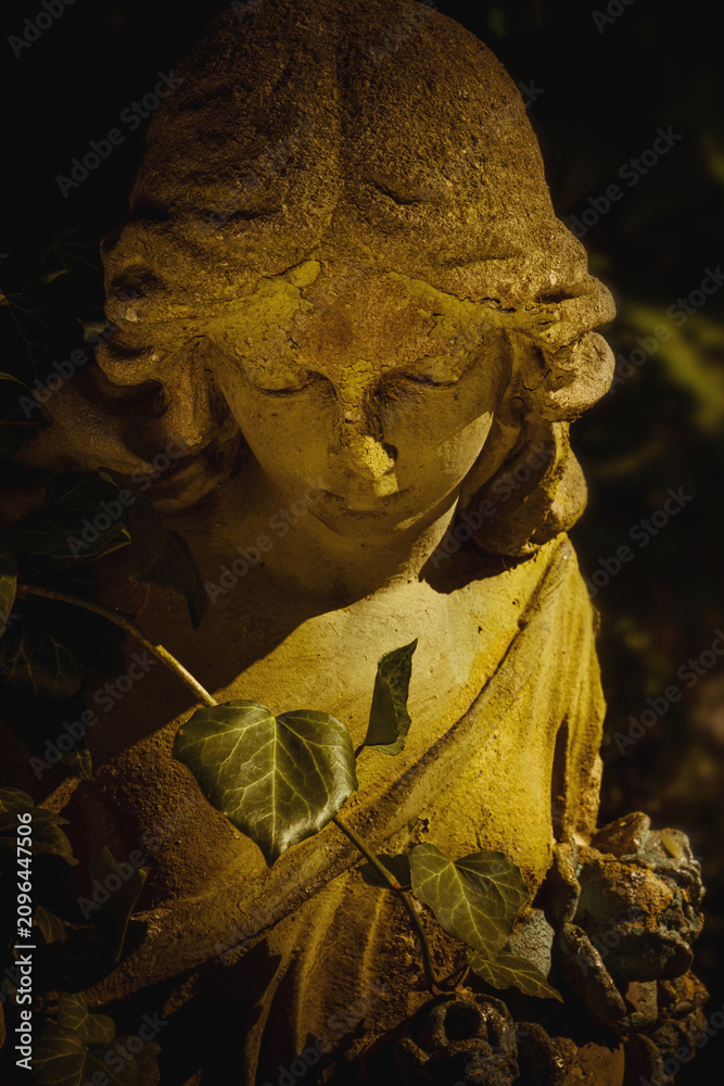 Fototapeta premium Ancient cemetery angel statue illuminated by warm golden light, symbolizing remembrance, hope, peace and eternal love.