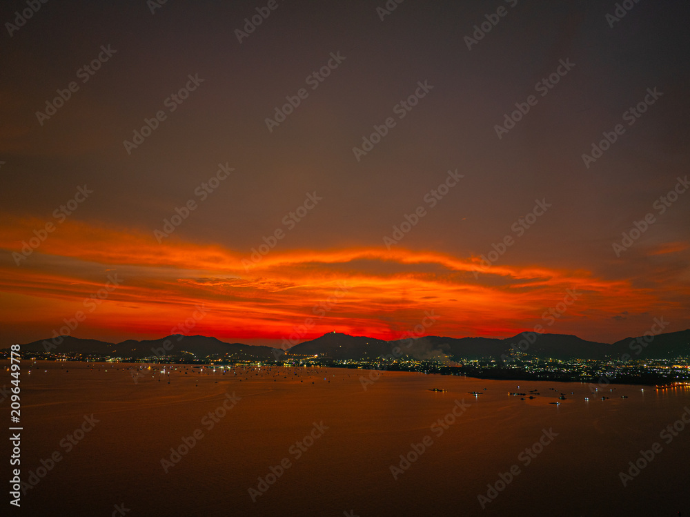 Fototapeta premium Scenic sunset seascape from above featuring Chalong Bay, Phuket Island, and the colorful evening sky, creating a peaceful tropical travel destination.