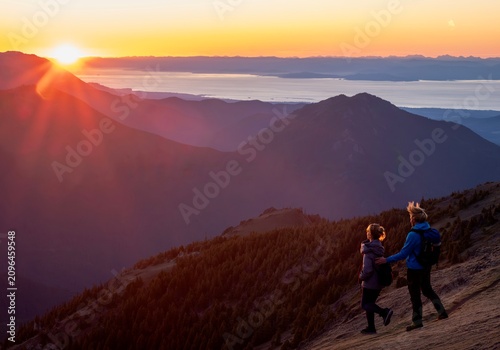 Couple hiking on mountains  watching sunrise over the ocean in Olympic National Park. Washington state. USA