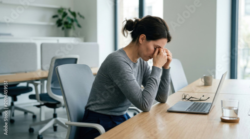 Woman Feeling Exhausted And Stressed At Her Desk In A Modern Office