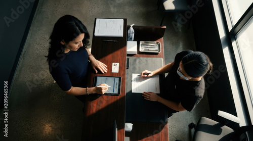 Two Professionals Collaborating On Digital And Paper Documents
