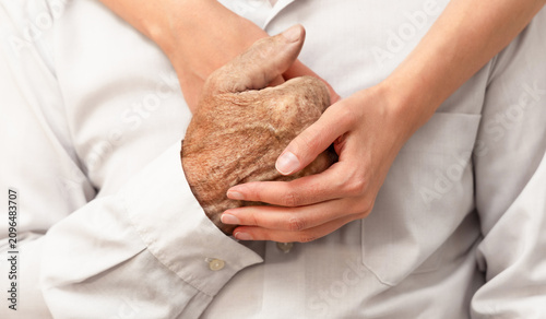 Foto A young woman's arms embrace and hold the hand of an elderly man