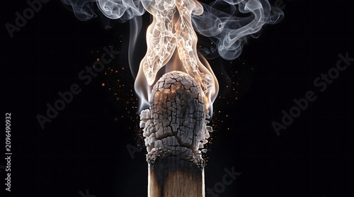 Burning match head with smoke and embers on black background