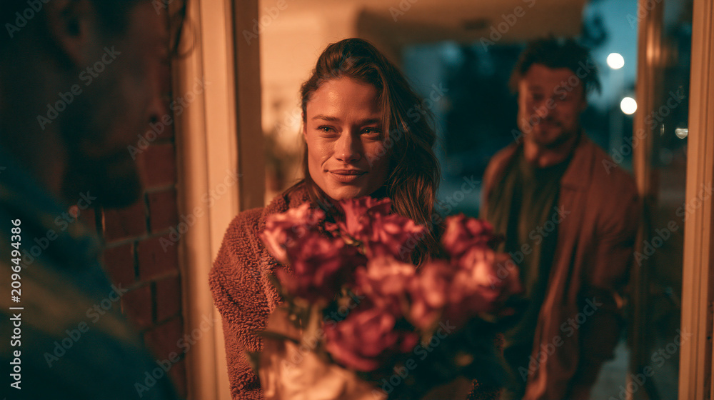 Obraz premium Evening Romantic Flower Presentation: Man Surprises Smiling Woman at Doorstep with Gesture of Love and Happiness