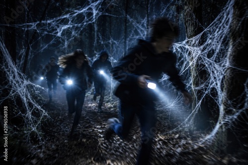 Group of teenagers running through spooky forest filled with thick spider webs