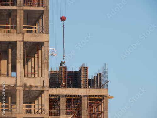 Bild auf Leinwand Industrial worker in a hardhat in uniform pour concrete and tower cranes at cons