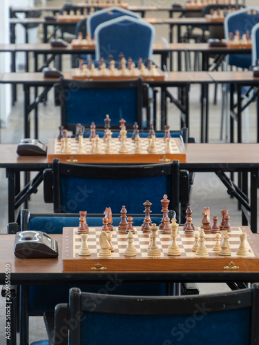 Obraz na płótnie Some chess boards with arranged pieces with a chess clock timer on the tables re