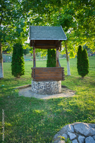 Foto A rustic wooden wishing well in a lush green park under dappled sunlight