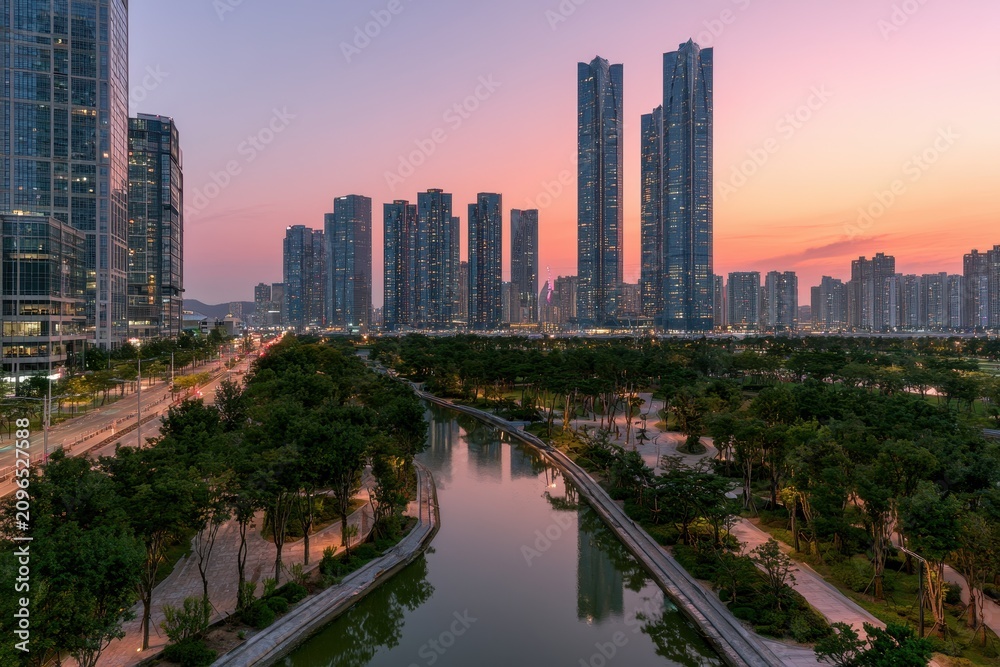 Fototapeta premium Golden hour twilight over Songdo Central Park: riverside walkways and futuristic skyline