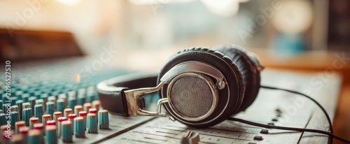 Sound equipment sits on a music mixing desk with headphones resting on it during a recording session in a studio