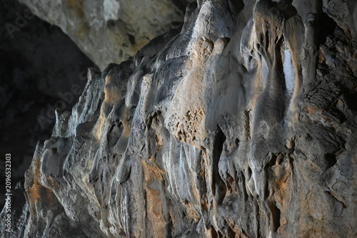 Foto Dramatic limestone stalactites and complex rock relief on the cave wall inside K