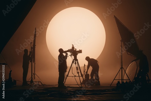 Cinematic silhouette of a film crew on a studio set with backlighting and haze