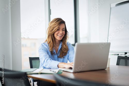 Happy businesswoman using her laptop in a modern office