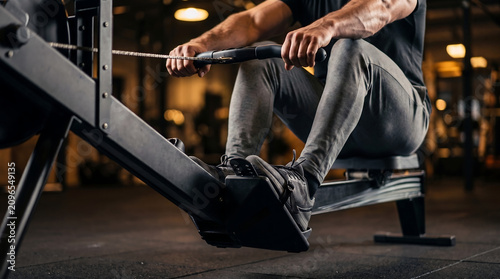 Side view of person using rowing machine in gym with exercise training strength physical gymnasium equipment wellness athletic muscular bodybuilding lifestyle
