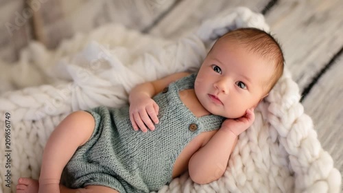Newborn baby lays on a cozy blanket in a warm room with soft light on a beautiful day