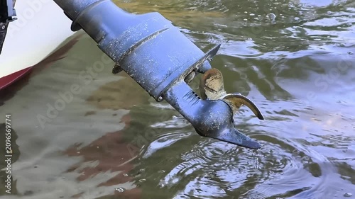 Close-up of an outboard motor propeller submerged in clear lake water while drifting