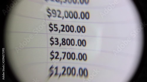 Close-up magnifying glass view of financial expense amounts on a digital screen