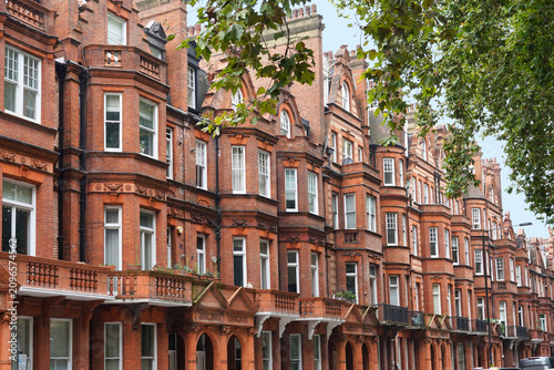 Long row of red brick townhouses with bay windows in Chelsea area of London