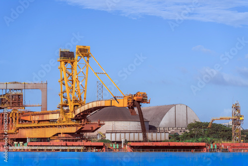 Fotografía Massive industrial site showing bulk ore being loaded onto a large bulk carrier vessel