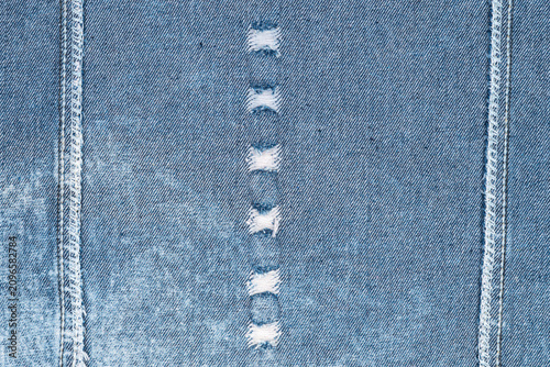 Foto Textured blue denim close up showing worn buttonholes contrasting white stitching
