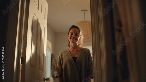 Girl smiles while standing at the door in a cozy home during the evening