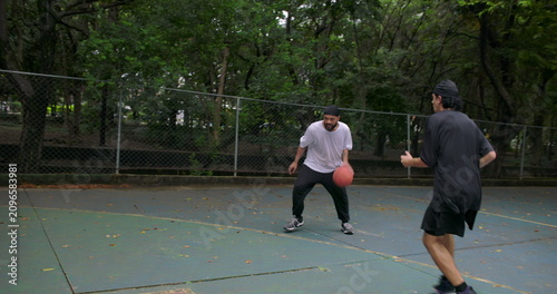 Photography Man of African descent runs toward basketball hoop and jumps to score during int
